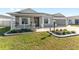 Gray house with a white porch and landscaping at 6764 Mary Loop, The Villages, FL 34762