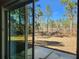 View of the backyard featuring a grassy lawn, mature trees, and a concrete patio seen through sliding glass doors at 8101 Sw 128Th Loop, Ocala, FL 34473