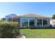 Back exterior view of house featuring a large windowed area, a covered patio, and landscaping at 9059 Se 177Th Grassmere St, The Villages, FL 32162