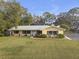 Yellow ranch home with mature landscaping and metal roof at 10406 Lakeshore Dr, Clermont, FL 34711
