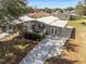Aerial view showcasing a renovated manufactured home with a spacious yard and driveway at 1404 Torrey Pines Dr, The Villages, FL 32159