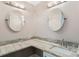 Vanity with granite countertop and two round mirrors at 1404 Torrey Pines Dr, The Villages, FL 32159