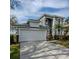 Two-story house with gray siding, white garage doors, and landscaping at 15245 Markham Dr, Clermont, FL 34714