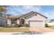 Tan one-story house with brown roof, two-car garage, and landscaping at 2029 Sloans Outlook Dr, Groveland, FL 34736