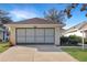 House front view with attached two-car garage and landscaping at 21837 Royal St Georges Ln, Leesburg, FL 34748