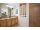 Well-lit bathroom showcasing a vanity with a granite countertop, glass block window, and a tiled walk-in shower at 2709 Astoria Ave, The Villages, FL 32162