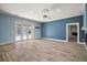 Open living room with blue accent wall, light hardwood floors, and French doors to the pool area at 29319 Old Mill E, Tavares, FL 32778