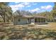 Exterior shot of home with screened patio and leafy backyard on a sunny day at 3380 Cr 528, Sumterville, FL 33585