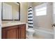 Bathroom with tub shower, wood vanity, and striped curtain at 6027 Spinnaker Loop, Lady Lake, FL 32159