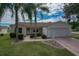 Charming single-story home with a well-manicured lawn, palm trees, and attached garage at 8338 Se 178Th Deveaux Ln, The Villages, FL 32162