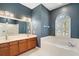 Bathroom featuring double vanity, garden tub under a window, and a separate glass-enclosed shower at 8920 Bridgeport Bay Cir, Mount Dora, FL 32757