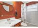 Bathroom with a tub and shower, vibrant orange wall, modern fixtures, and decorative shower curtain at 8920 Bridgeport Bay Cir, Mount Dora, FL 32757