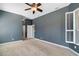 Spacious bedroom with neutral carpet, dark blue paint, a ceiling fan, and ample natural light at 8920 Bridgeport Bay Cir, Mount Dora, FL 32757
