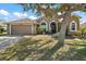 Inviting home exterior with a well-maintained lawn and mature tree providing shade, adding to its appeal at 8920 Bridgeport Bay Cir, Mount Dora, FL 32757