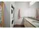 Bathroom with a stacked washer and dryer, double vanity, and shower at 8988 Silver Pl, Kissimmee, FL 34747
