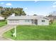 Gray house with teal accents, two-car garage, and spacious lawn at 9897 Se 178Th Pl, Summerfield, FL 34491
