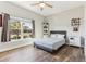 Bright bedroom with large window, gray bed, and wood-look floors at 10291 Se 69Th Ter, Belleview, FL 34420