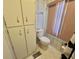 Bathroom featuring toilet, pink window blinds, and a linen closet at 114 Chestnut St, Leesburg, FL 34748