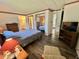 Bedroom featuring a queen bed, striped wallpaper, hardwood floors, and furnishings; bathroom access visible at 114 Chestnut St, Leesburg, FL 34748
