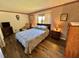 Bedroom featuring a queen bed, striped wallpaper, hardwood floors, and traditional furnishings at 114 Chestnut St, Leesburg, FL 34748