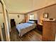 Bedroom featuring a queen bed, striped wallpaper, hardwood floors, and traditional furnishings at 114 Chestnut St, Leesburg, FL 34748