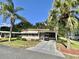 Charming single-story home with well-manicured lawn, mature palms, and covered carport with golf cart at 114 Chestnut St, Leesburg, FL 34748