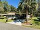 Tan mobile home with carport, palm trees, and manicured lawn at 114 Chestnut St, Leesburg, FL 34748