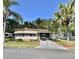 Charming single-story home with well-manicured lawn, mature palms, and covered carport with golf cart at 114 Chestnut St, Leesburg, FL 34748
