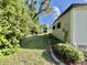 Side yard featuring lush greenery, manicured landscaping, and mature trees, providing a serene outdoor space at 114 Chestnut St, Leesburg, FL 34748
