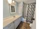 Well-lit bathroom with a white vanity, cabinets, and tub-shower combo with patterned curtain at 169 Bougainvillea Dr, Leesburg, FL 34748