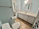 Bathroom with a long vanity, sink, mirror, and a toilet; view into another bathroom at 169 Bougainvillea Dr, Leesburg, FL 34748