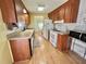 Galley kitchen with wood cabinets, white appliances, and laminate flooring at 169 Bougainvillea Dr, Leesburg, FL 34748