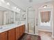 Bathroom featuring double sinks, wooden cabinets, a tile shower, and arched doorways at 17525 Se 121St Cir, Summerfield, FL 34491