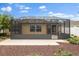 Backyard featuring a screened lanai, landscaped garden beds, and a well-maintained lawn at 1941 Loadstar Ave, The Villages, FL 32162