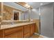 Double vanity with granite countertops, wood cabinets, and glass-enclosed shower in the on-suite bathroom at 1941 Loadstar Ave, The Villages, FL 32162