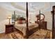 Elegant primary bedroom with a four-poster bed, decorative ceiling, and dark-wood furniture, exuding sophistication at 1941 Loadstar Ave, The Villages, FL 32162