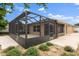 This showcases the home's screened lanai, landscaping, and overall exterior design at 1941 Loadstar Ave, The Villages, FL 32162