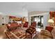 Bright living room with hardwood floors, multiple seating areas, and an open layout flowing into the kitchen and dining area at 1941 Loadstar Ave, The Villages, FL 32162