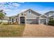 Two-story house with gray siding, three-car garage, and a brick driveway at 2064 Lula Rd, Minneola, FL 34715