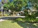 Single-story home with white exterior, large tree, and circular driveway at 208 First St, Tavares, FL 32778