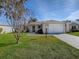 Tan house with white garage door and landscaped lawn at 2371 Wilson Way, The Villages, FL 32162