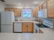 View of kitchen with wood cabinets, white appliances, and tile floor at 2371 Wilson Way, The Villages, FL 32162