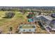 Aerial shot featuring community shuffleboard courts, pool, clubhouse, and nearby golf course with mature trees at 2420 Prairie Dunes, Clermont, FL 34711