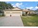 Tan two-story house with three car garage and lush landscaping at 2420 Prairie Dunes, Clermont, FL 34711