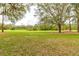 Scenic view of a lush green golf course with mature trees and a grassy area at 25921 San Rafael Ct, Howey In The Hills, FL 34737