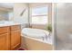 Bright bathroom featuring a soaking tub with tile surround and large window at 26709 Augusta Springs Cir, Leesburg, FL 34748