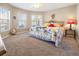 Bright main bedroom featuring a floral comforter, bay window, and neutral carpet at 26709 Augusta Springs Cir, Leesburg, FL 34748