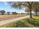 A street view of a property with a well-maintained lawn and mature trees at 26709 Augusta Springs Cir, Leesburg, FL 34748