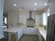 Well-lit kitchen featuring white cabinets, stainless steel hood, mosaic backsplash, and an eat-in island at 314 Salt Marsh Ln, Groveland, FL 34736