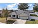 Single-story house with gray roof, attached garage, and well-manicured lawn at 36628 Grand Island Oaks Cir, Grand Island, FL 32735